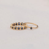 A Birthstone Ring in Sapphire - September and The Iris Bouquet Ring in yellow gold against a light grey background. 