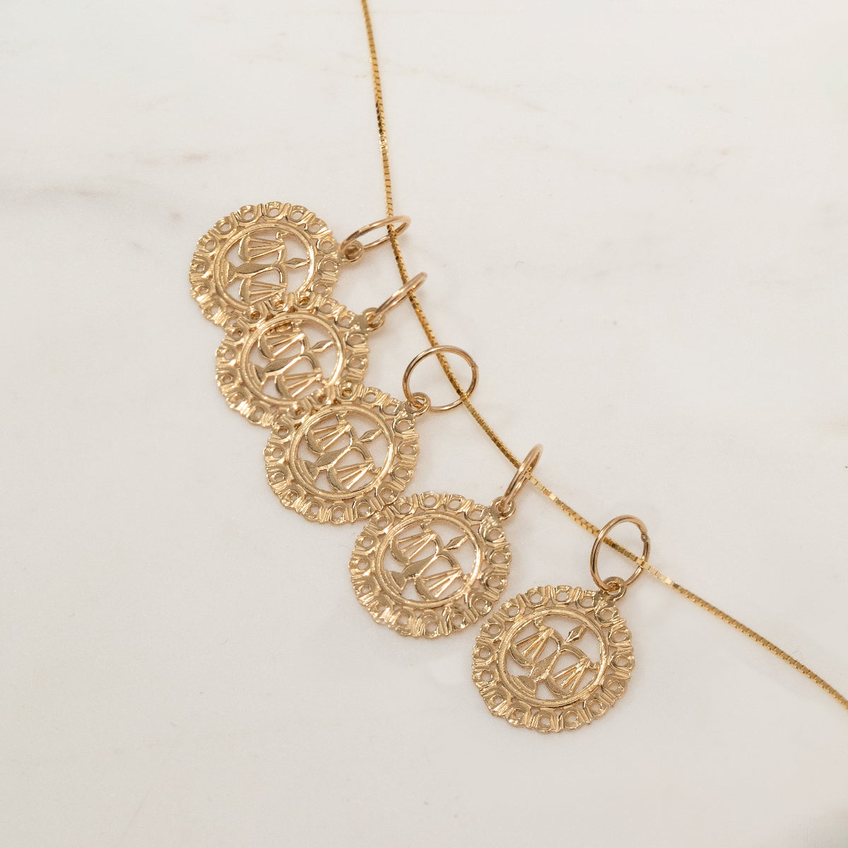 Five Libra Zodiac Pendants on The Slide Chain on an off-white background. 