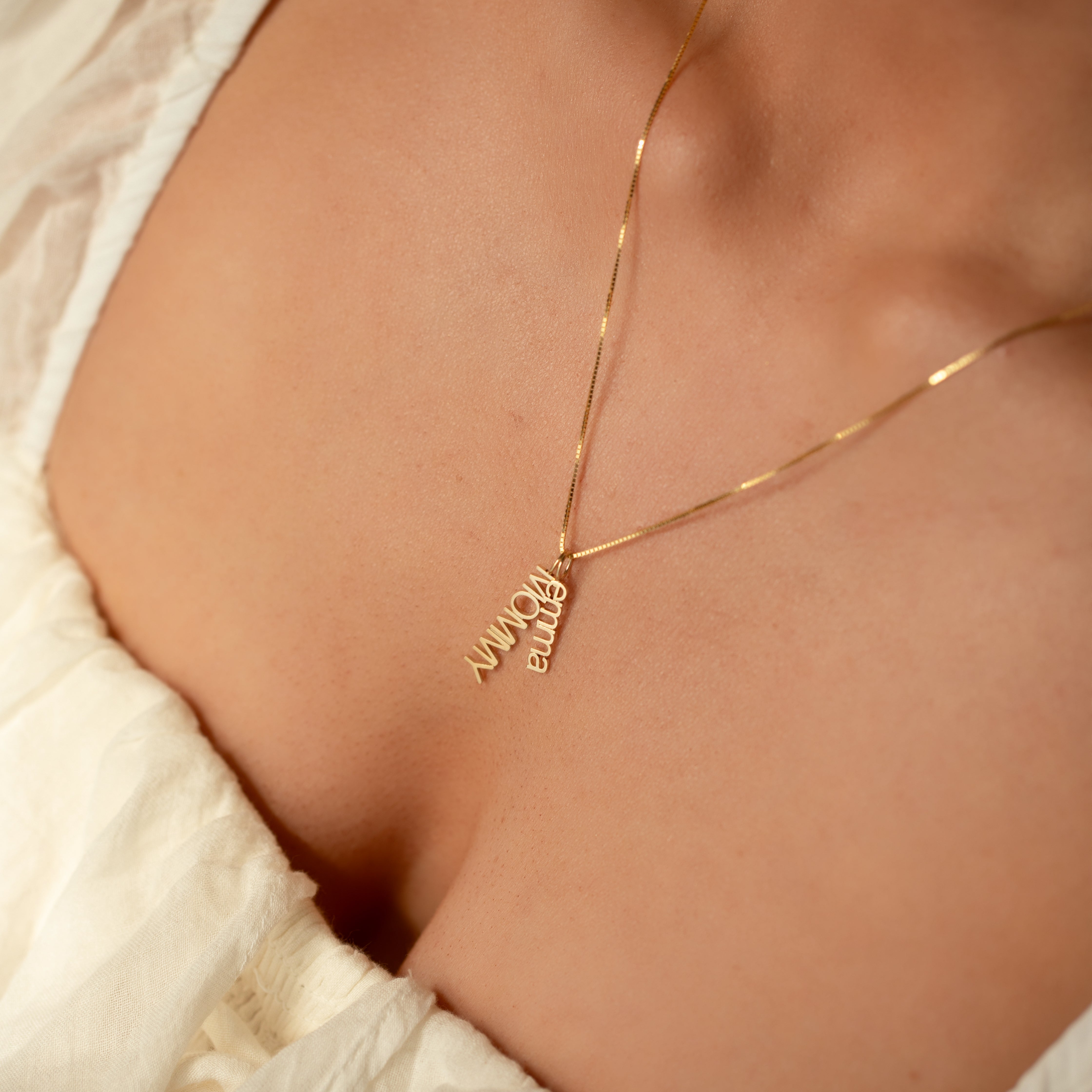 14k gold MOMMY word plate charm necklace styled with a nameplate pendant on model.