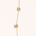 Gold necklace with small rectangular pendants on a white background