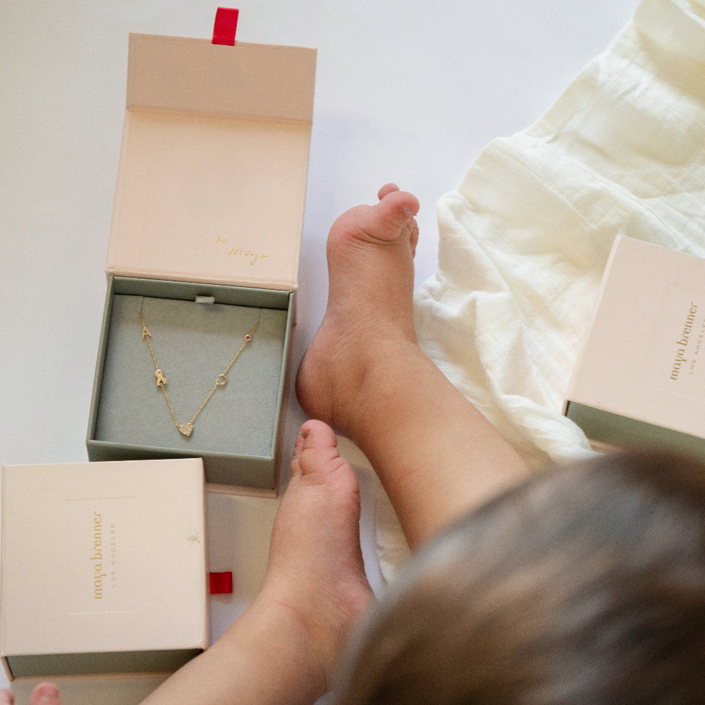 Child's feet near a box with a gold necklace inside, on a light background