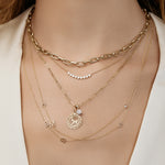 Multiple gold necklaces with various pendants on a model