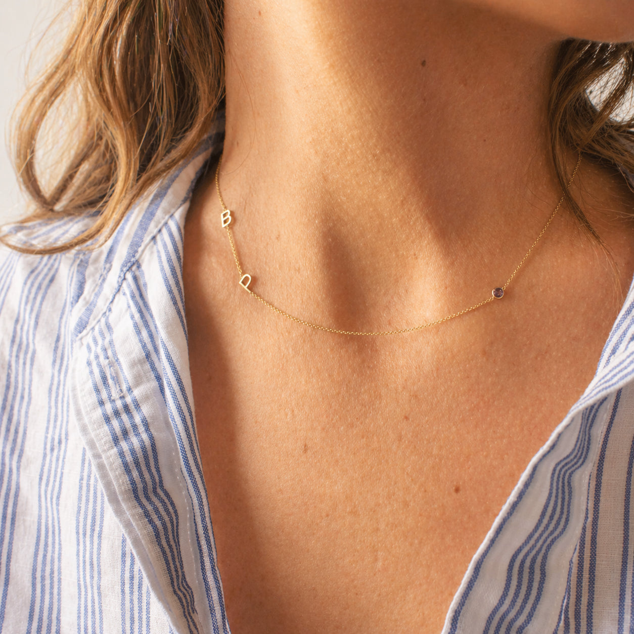 Gold necklace on a person wearing a blue and white striped shirt