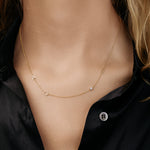 Gold necklace with "A",  "C", "E" and a birthstone on a model.