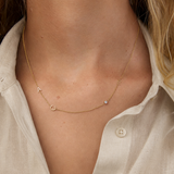 Necklace with small letters and a birthstone on a person wearing a light-colored shirt.
