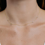 Gold necklace with horseshoe and letter charms on a person's neck