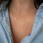 Necklace with small pendants worn by a person in a denim shirt
