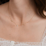 Custom necklace with a small heart pendant on a person wearing a lace top