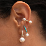 Model wearing the Turquoise Huggie with a Mini Pearl Earring Charm and pearl ear cuff.