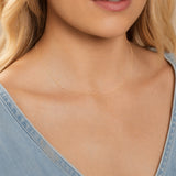 Close-up of a woman's neck wearing a gold necklace with a letter F charm. 