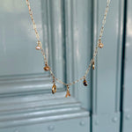 Gold necklace with charms on a light blue background
