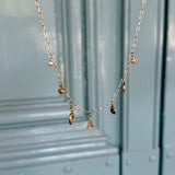 Gold necklace with charms on a light blue background