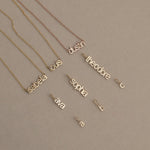 Gold name necklaces on a beige background