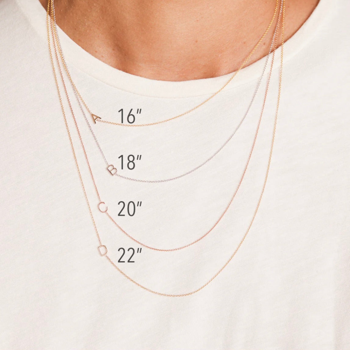 Gold necklaces of different lengths displayed on a white shirt.