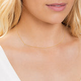 Close-up of a person wearing a delicate gold necklace with a letter Y charm.
