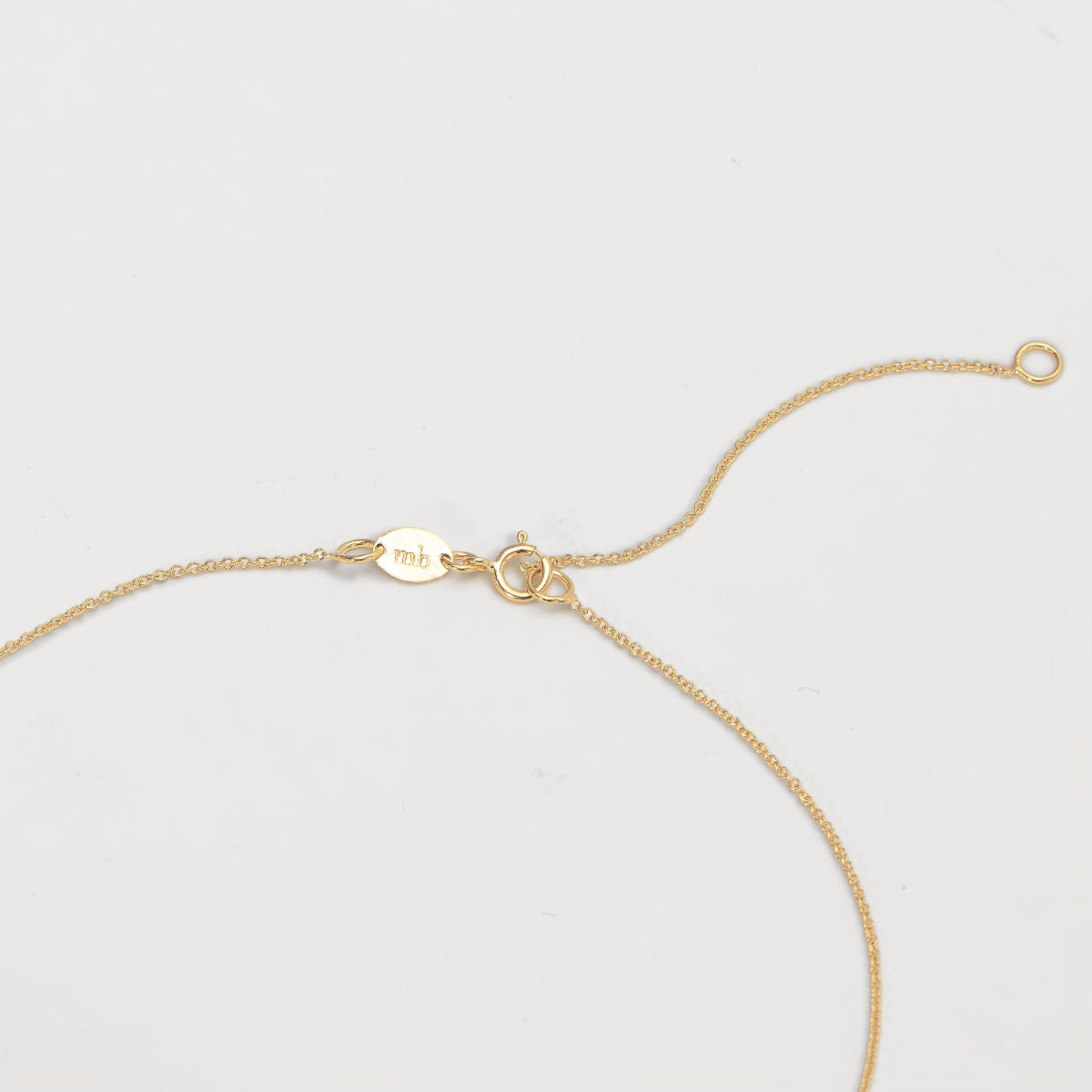 The back of a necklace in yellow gold on an off-white background. 