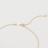 The back of a necklace in yellow gold on an off-white background. 