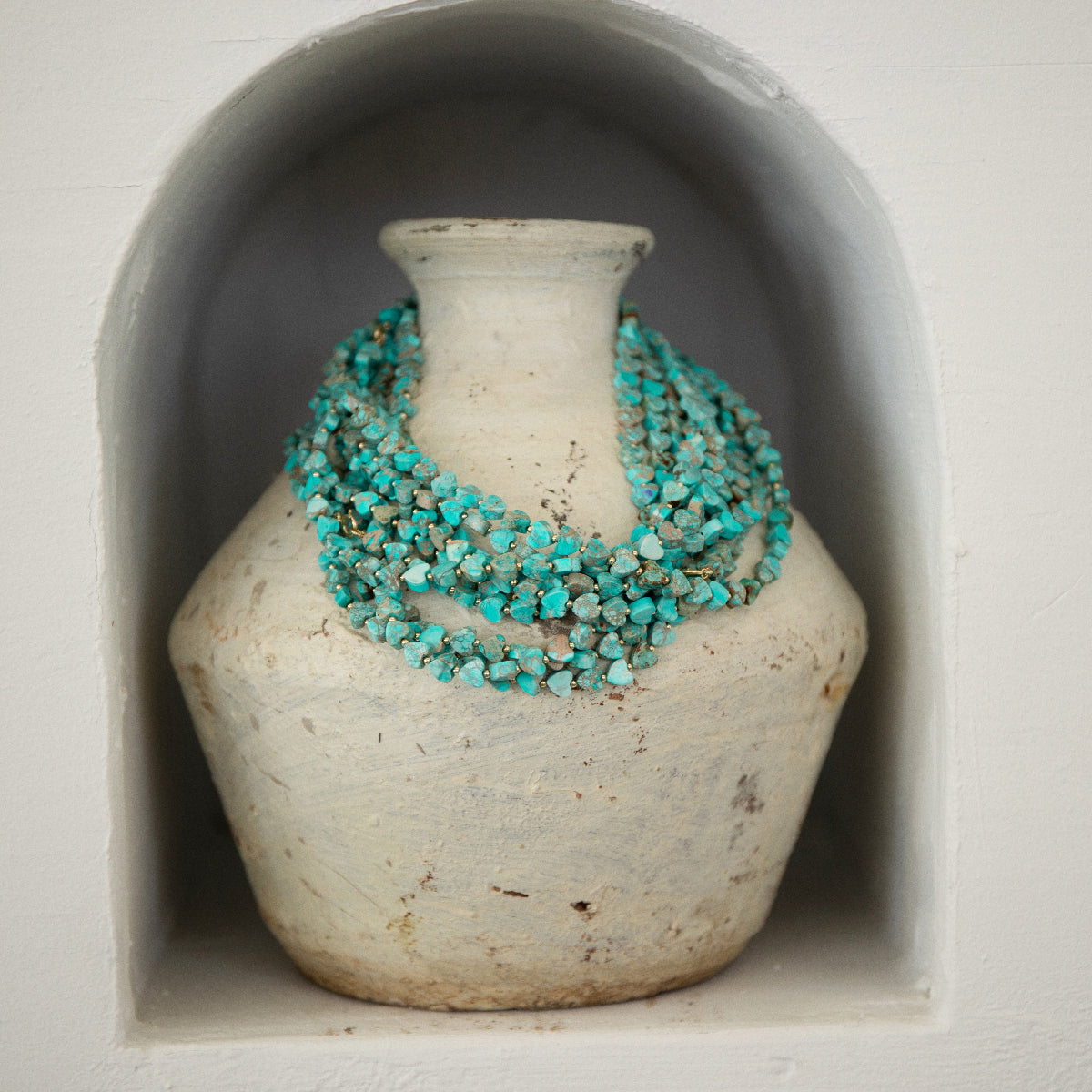 Several Endless Summer Necklaces - Sea + Sky on a textured cream vase. 