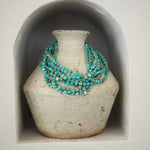 Several Endless Summer Necklaces - Sea + Sky on a textured cream vase. 