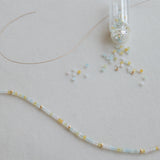 An Endless Summer Bracelet – Saint-Tropez laid out with a small clear container of beads on a light grey background.