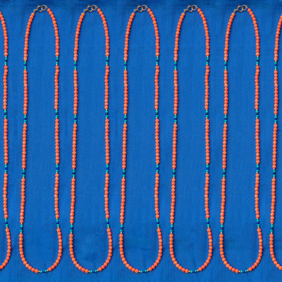 Several Endless Summer Necklaces - Calypso laid against a blue fabric background.