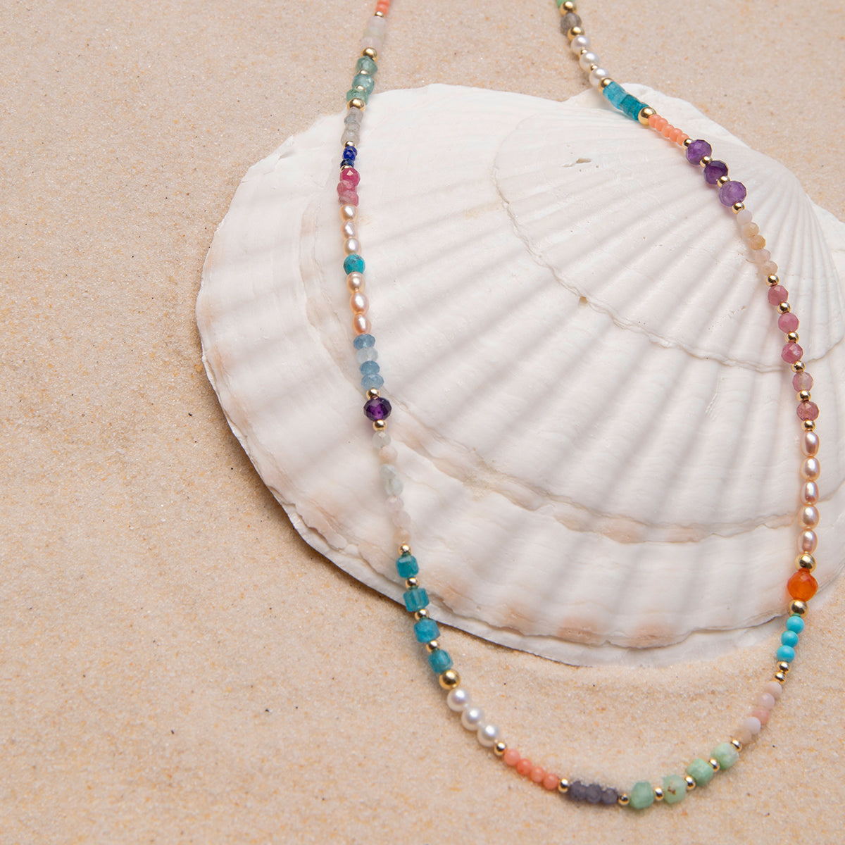An Endless Summer Necklace – Capri laid on top of a shell in the sand.