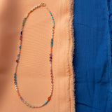 An Endless Summer Necklace - Capri against a blue and orange fabric background. 