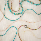 Several Endless Summer Necklaces (Sweet Escape, Coral Reef, Pink Sands, Sea + Sky, Turqs + Caicos and Santorini) on a cream fabric background.  