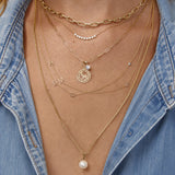 Close-up of layered gold necklaces with a denim jacket