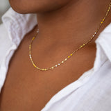 A close-up of a neck wearing a Confetti Necklace - Yellow, styled with a white shirt. 