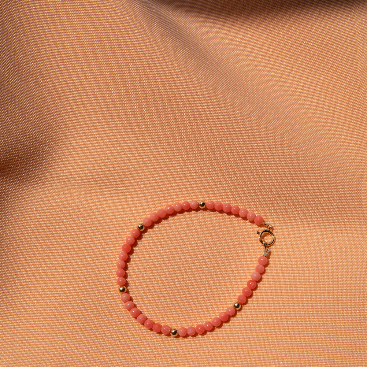 An Endless Summer Bracelet - Mykonos on a light orange fabric background. 