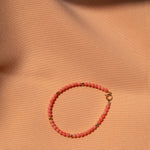 An Endless Summer Bracelet - Mykonos on a light orange fabric background. 