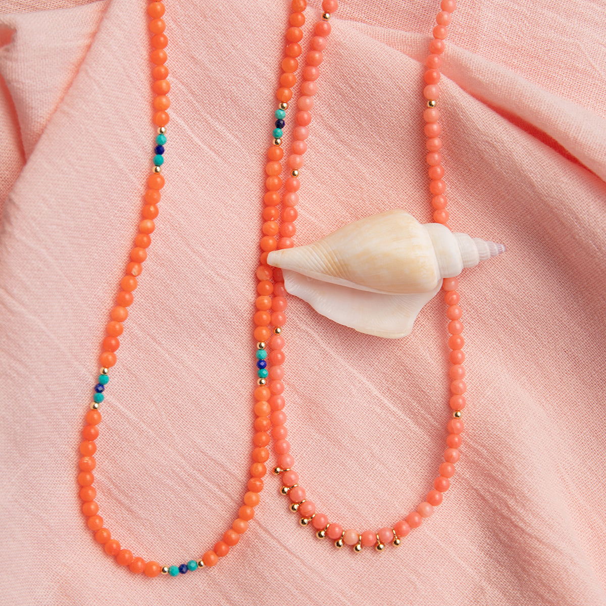 Endless Summer Necklaces - Mykonos and Calypso on a light pink fabric background with a shell. 