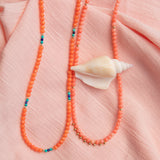 Endless Summer Necklaces - Mykonos and Calypso on a light pink fabric background with a shell. 