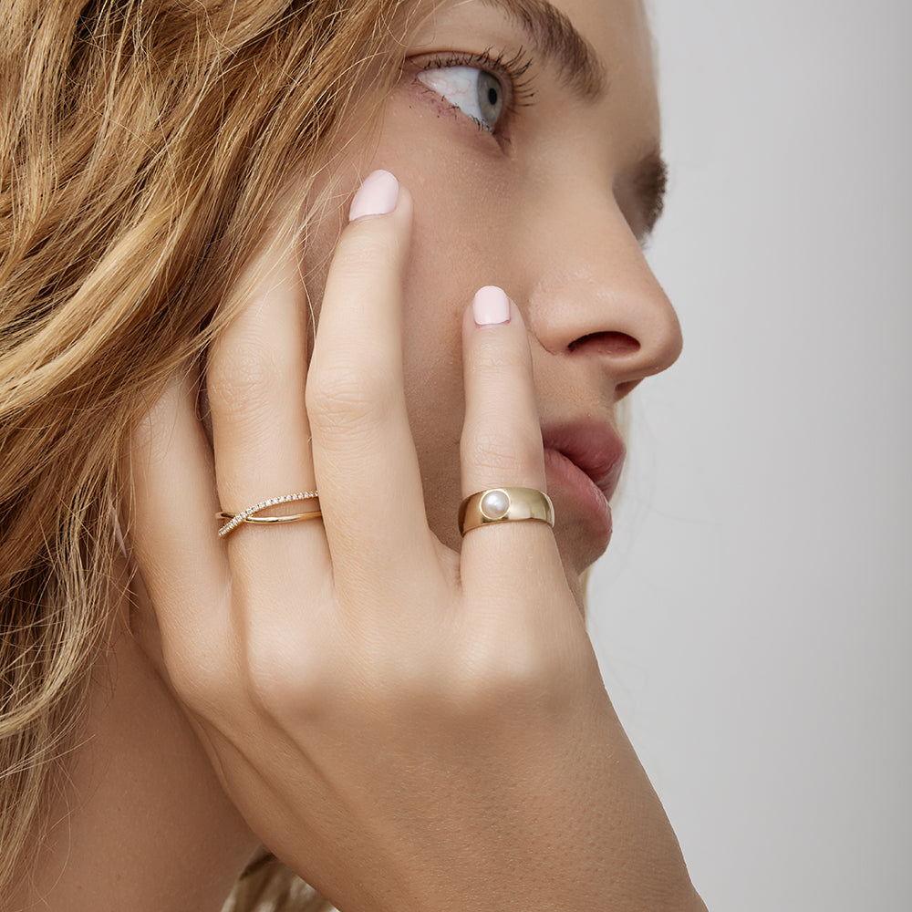Close-up of a woman's hand with gold rings on a neutral background