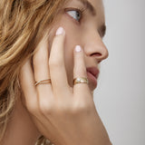 Close-up of a woman's hand with gold rings on a neutral background