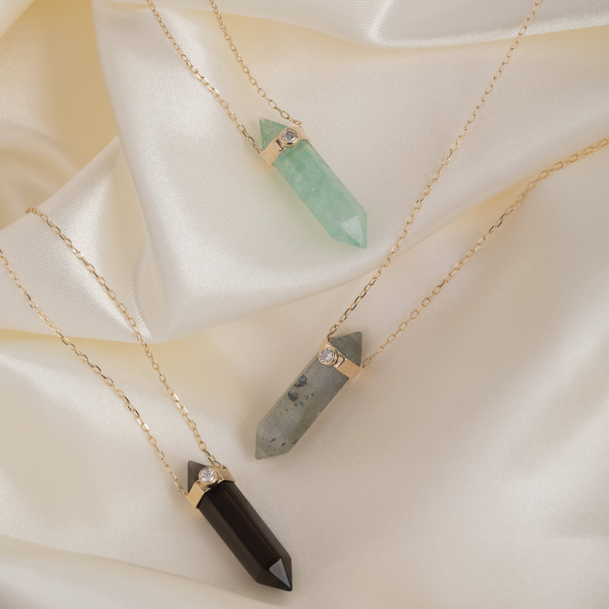 Three Retreat Necklaces - Protection, Courage and In Flow on a cream silk background. 