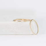 Delicate Trio Stacking Rings in yellow gold on a white surface and background. 