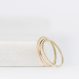 Delicate Trio Stacking Rings in yellow gold on a white surface and background. 