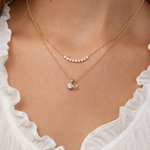 Diamond Arc Layering necklace with a Gold Letter Jumble Necklace on a person wearing a white top