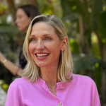 A woman wearing a Diamond Cascade Earring with blonde hair and a pink top against a green leafy blurred background.