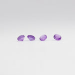 Four amethyst gemstones on a light grey background. 