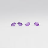 Four amethyst gemstones on a light grey background. 