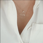 Close-up of a décolletage wearing a FEMME Necklace and a rainbow pendant necklace with a white shirt. 