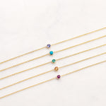 Set of gold necklaces with colorful gemstones on a light gray background