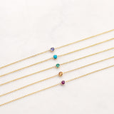 Set of gold necklaces with colorful gemstones on a light gray background