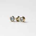 Three gold aquamarine birthstones on a light grey background.
