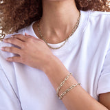 A close-up of a woman wearing a Bold Link Chain and two Bold Link Bracelets, styled with a white t-shirt.