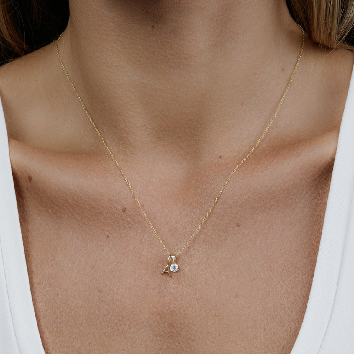 A woman's decellotage wearing a yellow gold Signature Cable Chain with a Gold Letter Jumble - A. 