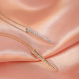 Two Love Struck Diamond Necklaces (one in yellow gold and the other in white gold) on a light orange silk background. 